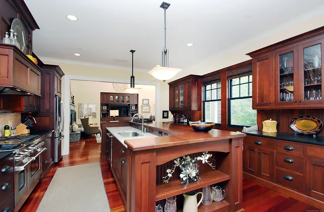 a kitchen with stainless steel appliances granite countertop a stove a sink dishwasher and a dining table with the living room view