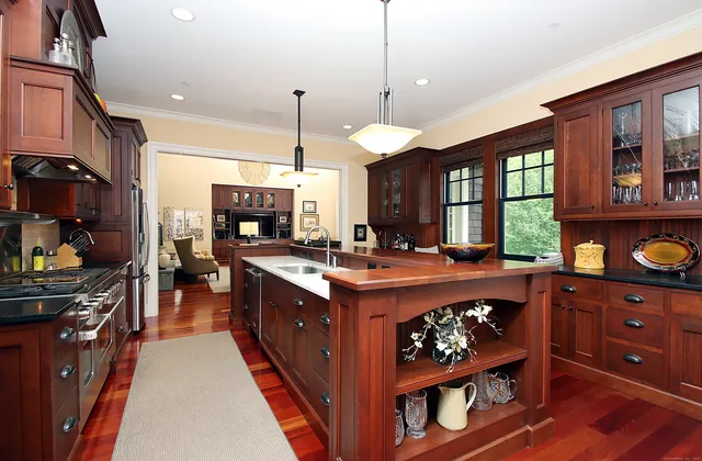 a large kitchen with stainless steel appliances granite countertop a stove a sink dishwasher and wooden cabinets with wooden floor