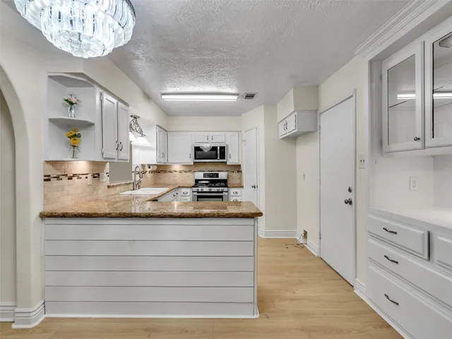 a kitchen with granite countertop a stove sink and microwave
