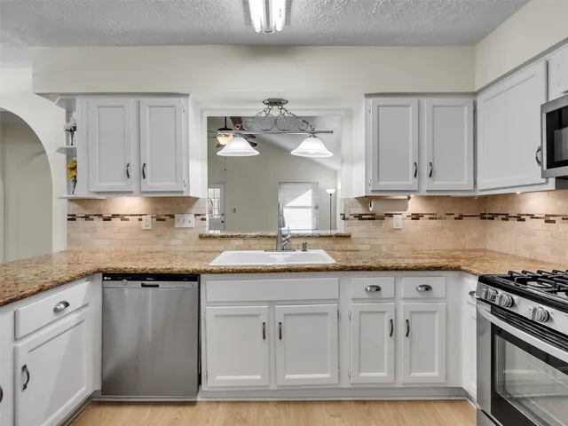 a kitchen with granite countertop white cabinets and white appliances
