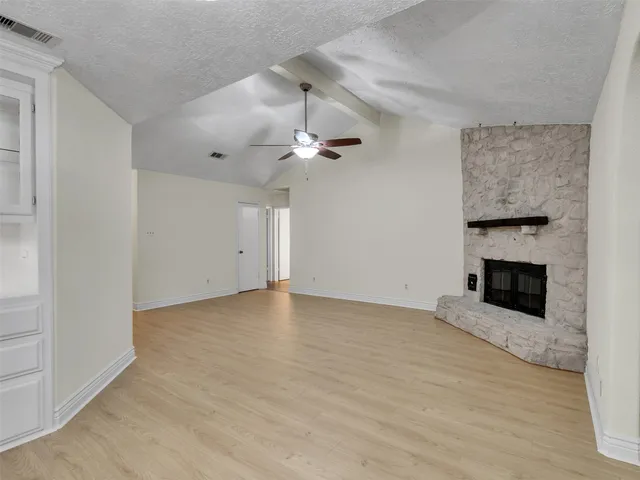 a view of an empty room with a fireplace and a window
