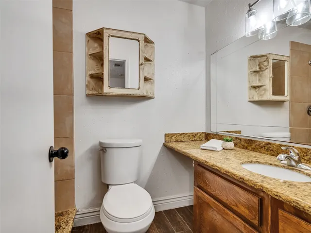 a bathroom with a granite countertop toilet sink and mirror