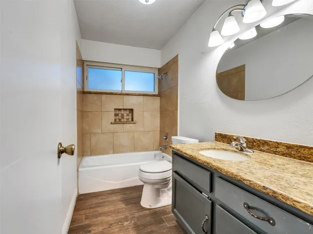 a bathroom with a granite countertop sink a toilet and mirror