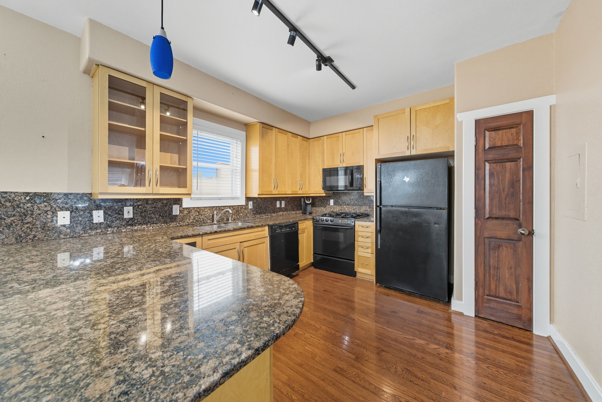 3015 Chenevert Street, Unit 1 Houston, TX 77004 - Photo 7 of 10 a kitchen with stainless steel appliances granite countertop a refrigerator a sink a stove and dishwasher with wooden floor