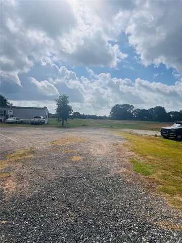 a backyard of a house with lawn chairs and a large tree