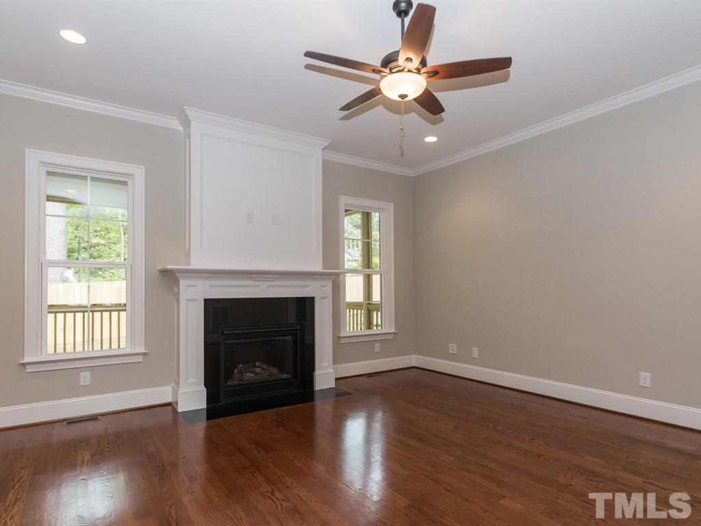 6402 Rosny Road Raleigh, NC 27613 - Photo 4 of 25 an empty room with wooden floor fireplace and windows