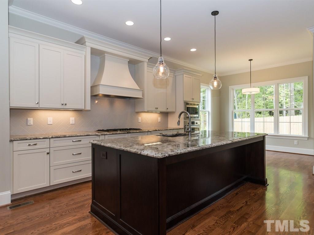 6402 Rosny Road Raleigh, NC 27613 - Photo 7 of 25 a kitchen with granite countertop a stove a sink wooden floor and cabinets