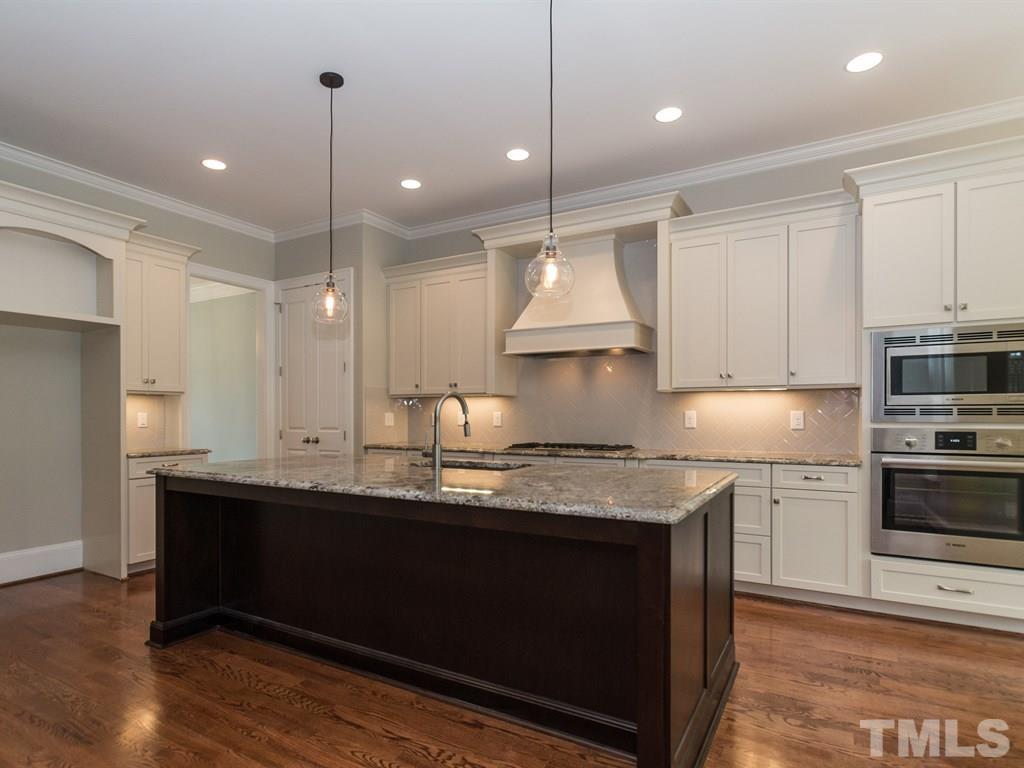 6402 Rosny Road Raleigh, NC 27613 - Photo 9 of 25 a kitchen with kitchen island granite countertop a sink a center island stainless steel appliances and cabinets