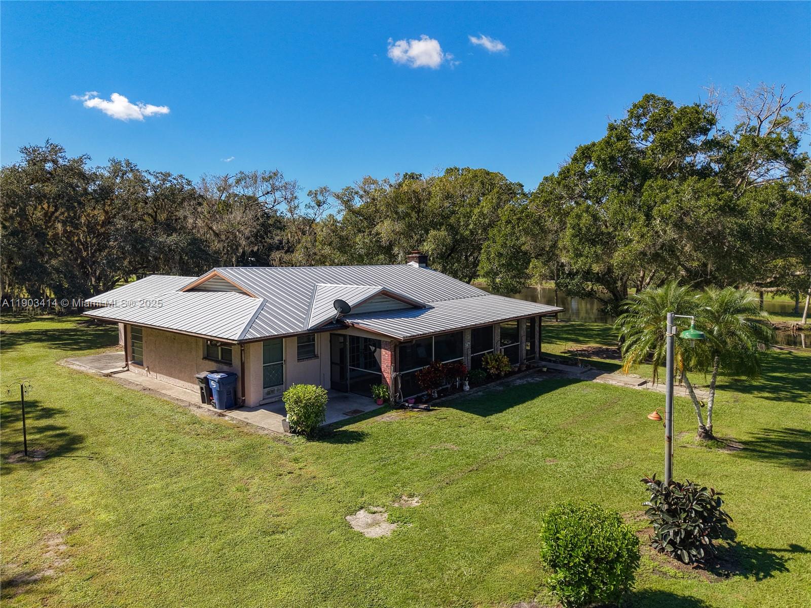 4419 Loblolly Bay Road Southwest LaBelle, FL 33935 - Photo 6 of 49 a view of a big house with a big yard and potted plants