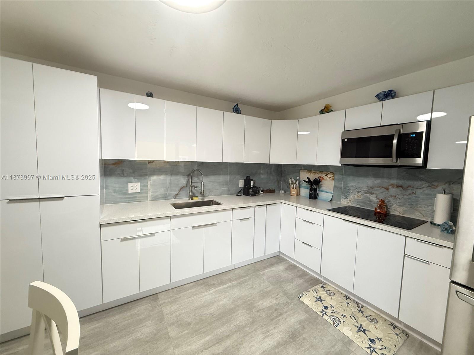 60 Southeast Marlin Avenue Key Largo, FL 33037 - Photo 34 of 40 a kitchen with granite countertop a sink a stove a microwave and cabinets