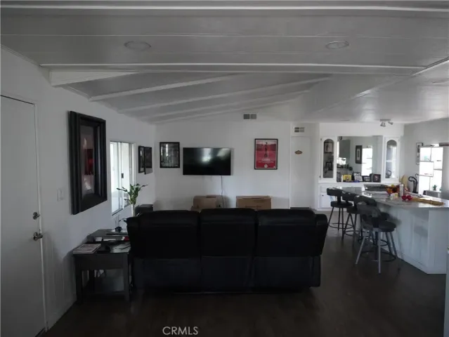 a living room with furniture a flat screen tv and kitchen view