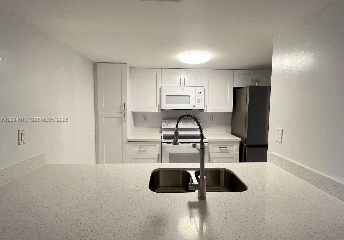 7075 Northwest 186th Street, Unit C205 Hialeah, FL 33015 - Photo 2 of 4 a kitchen with kitchen island a sink and refrigerator