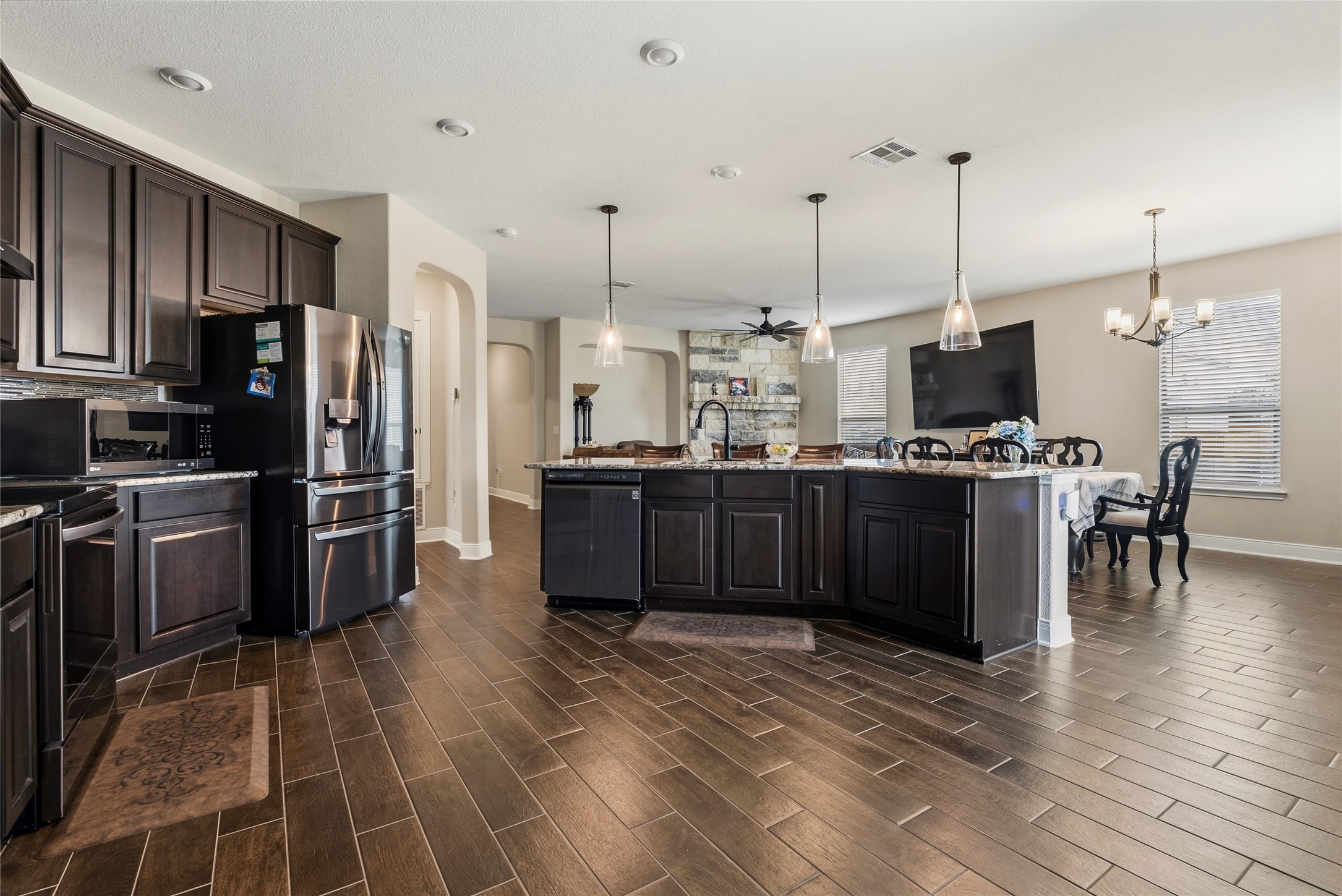 105 West Point Way Elgin, TX 78621 - Photo 23 of 27 Expansive kitchen featuring dark wood cabinetry, stainless steel appliances, a large central island with pendant lighting, and wood-finish flooring