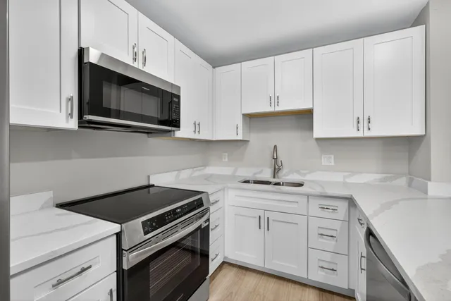 a kitchen with white cabinets and stainless steel appliances