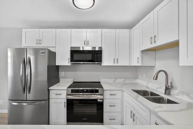 a kitchen with white cabinets stainless steel appliances and sink