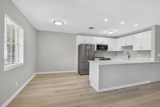 a kitchen with stainless steel appliances a refrigerator sink and microwave