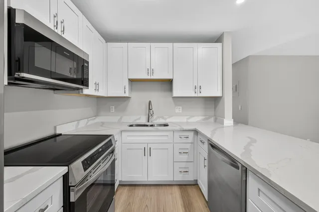 a kitchen with stainless steel appliances white cabinets granite counter tops and a stove