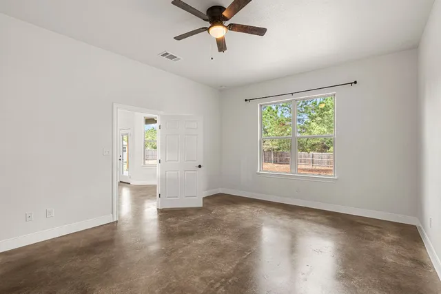 an empty room with windows and fan