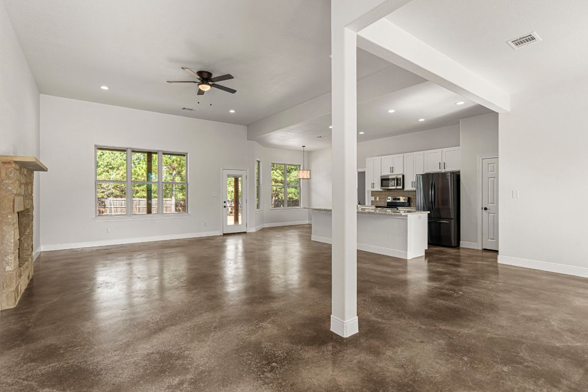 203 Cardinal Loop Paige, TX 78659 - Photo 3 of 36 an empty room with large windows and kitchen view