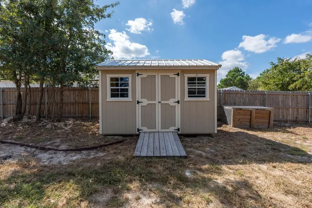 a view of a house with a small yard and a large tree