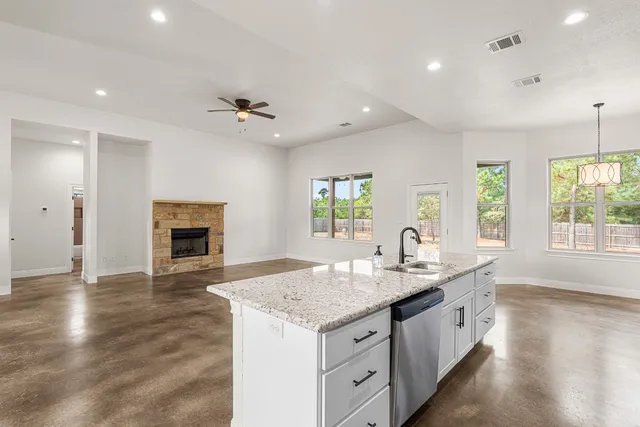an open kitchen with granite countertop a stove and a wooden floors