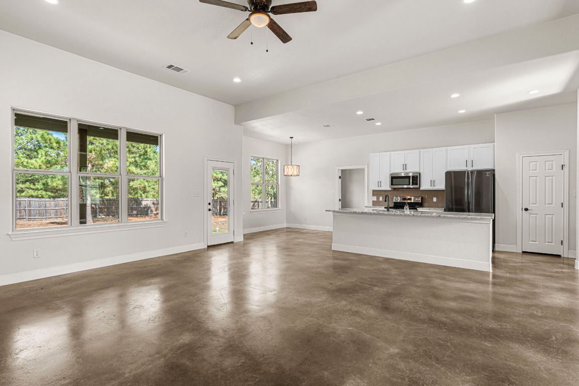 203 Cardinal Loop Paige, TX 78659 - Photo 9 of 36 a view of kitchen with stainless steel appliances kitchen island granite countertop a refrigerator a oven a sink with a dining table and chairs