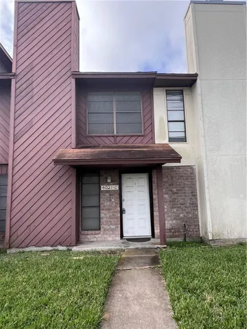 a brick house with a small yard and plants