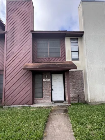 a brick house with a small yard and plants