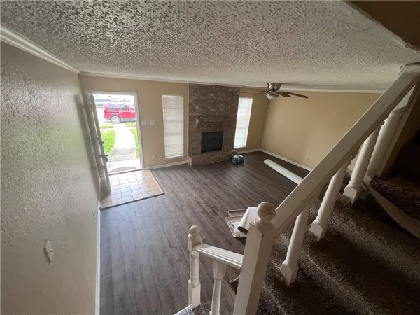 a view of an empty room with wooden floor and a fireplace