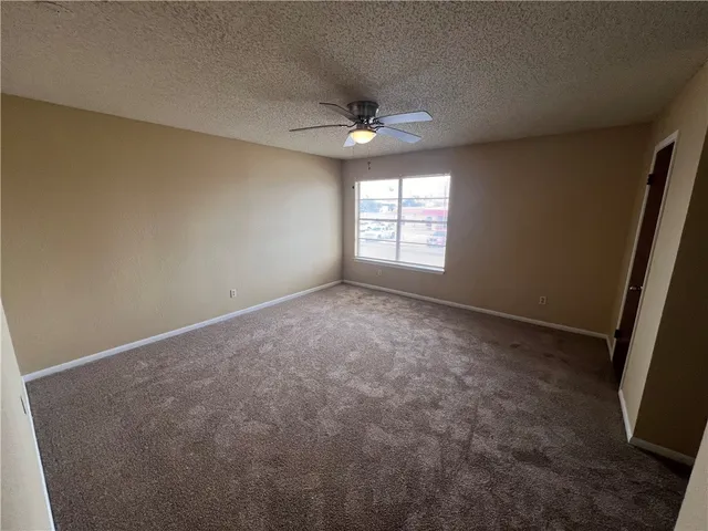 an empty room with a window and a ceiling fan