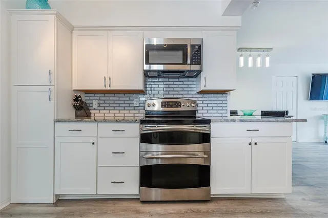 a kitchen with white cabinets and stainless steel appliances