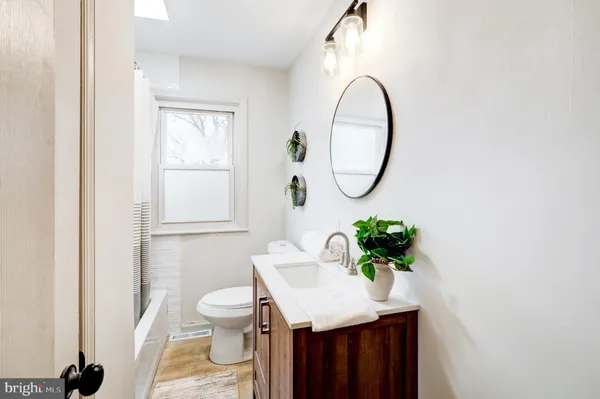 a bathroom with a granite countertop sink a toilet and a mirror