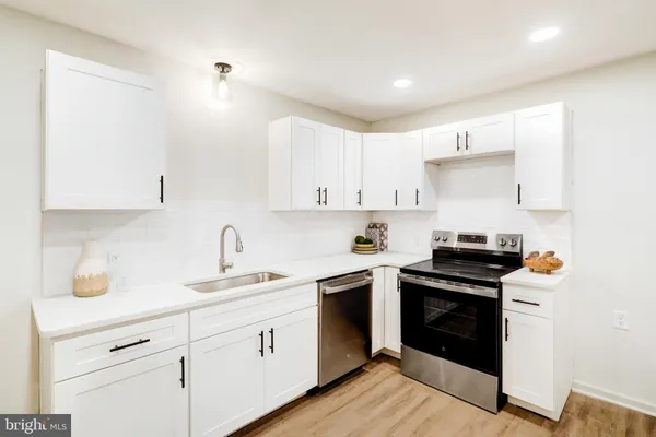 a kitchen with cabinets stainless steel appliances a sink and wooden floor