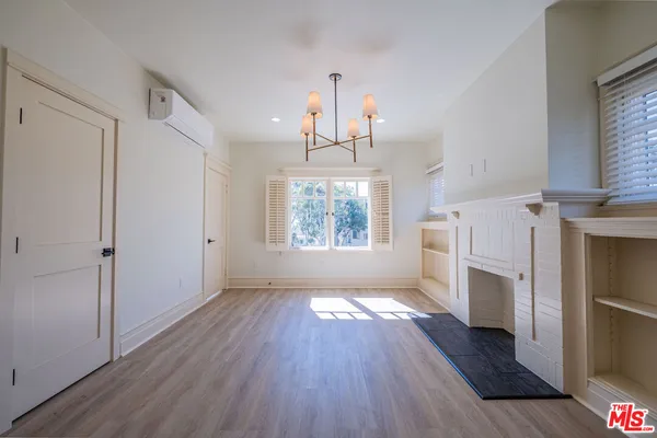 a view of an empty room with wooden floor fireplace and a window
