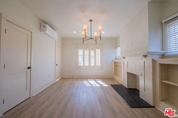 a view of a room with wooden floor fireplace and windows