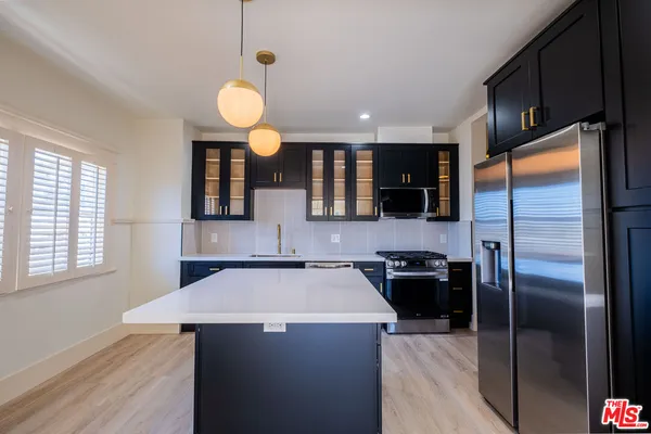 a kitchen with a refrigerator a sink cabinets and wooden floor