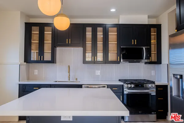 a kitchen with stainless steel appliances granite countertop a stove a sink and a microwave
