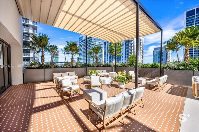 a view of a patio with couches and chairs under an umbrella