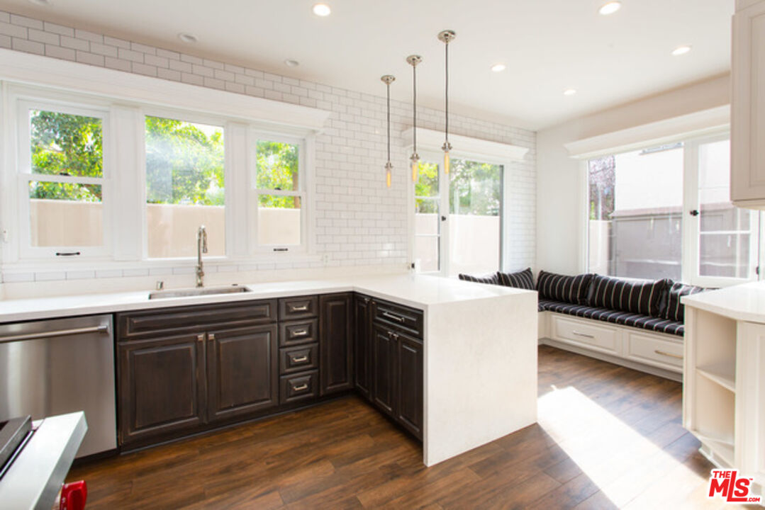 a large kitchen with kitchen island granite countertop a large window a sink stainless steel appliances and cabinets