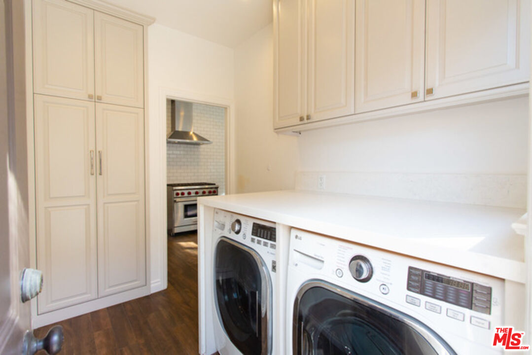 153 North Arnaz Drive Beverly Hills, CA 90211 - Photo 13 of 20 a view of washer and dryer with kitchen in the background