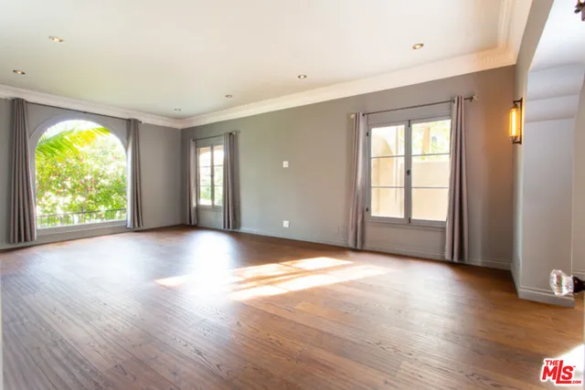 a view of an empty room with wooden floor and windows