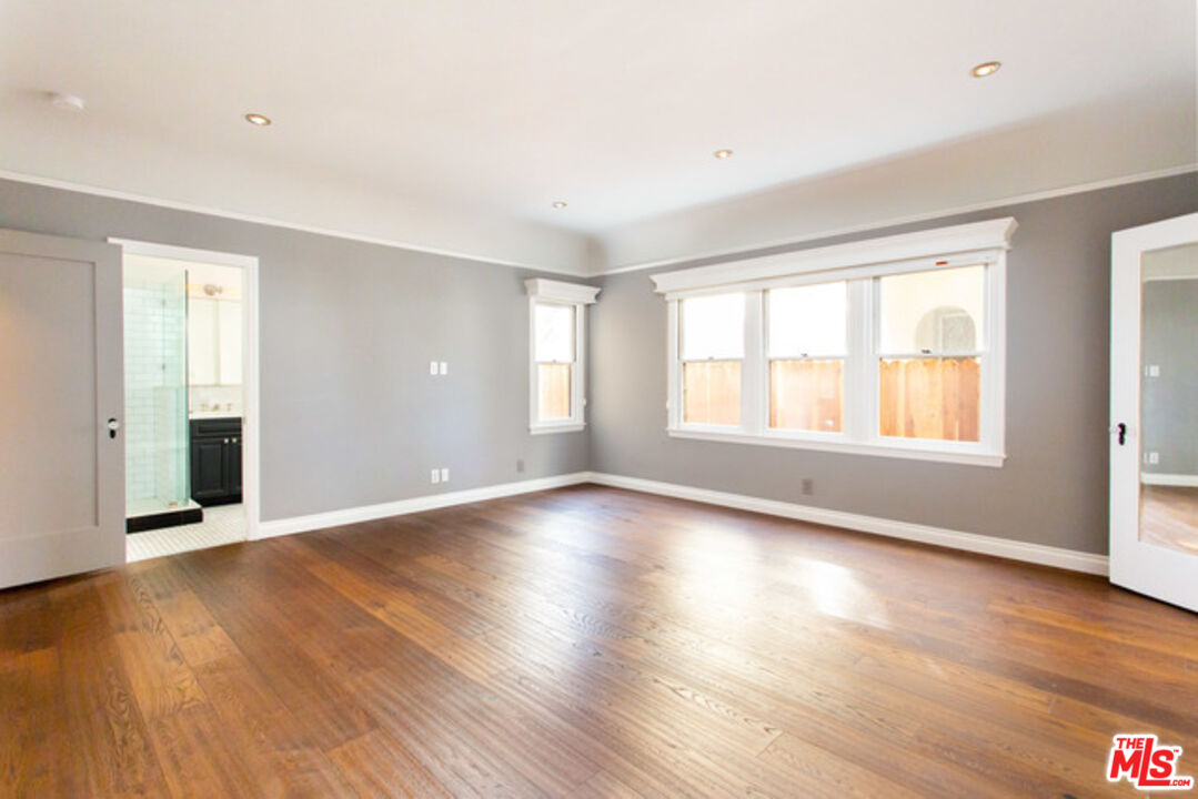 153 North Arnaz Drive Beverly Hills, CA 90211 - Photo 5 of 20 an empty room with wooden floor and windows