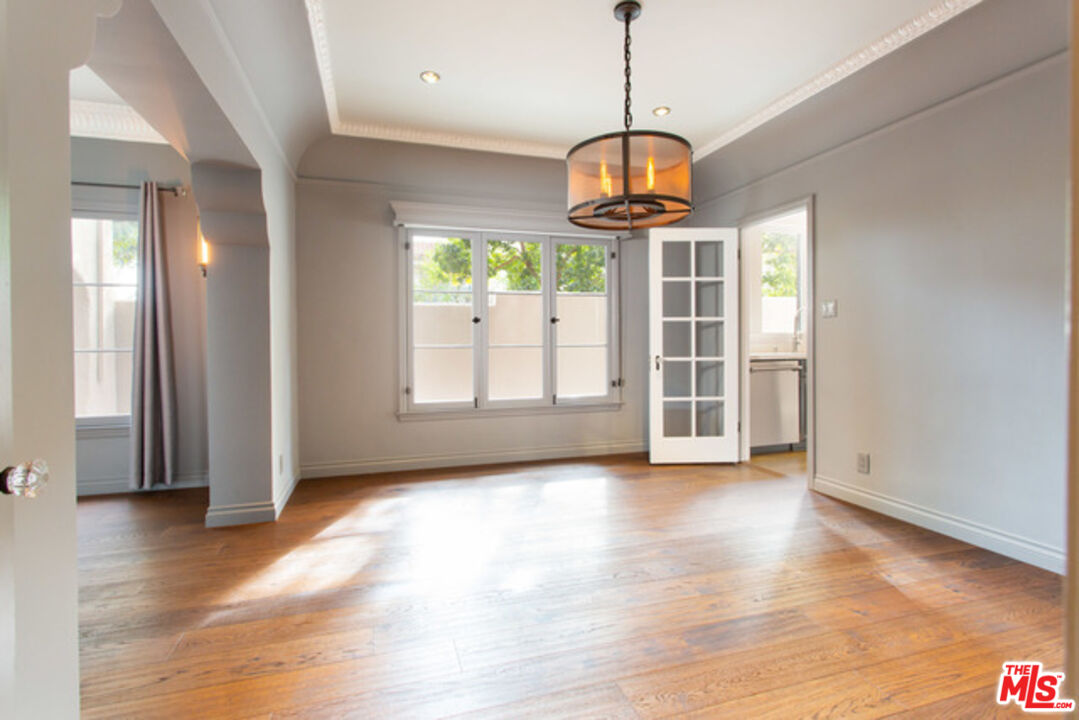 153 North Arnaz Drive Beverly Hills, CA 90211 - Photo 7 of 20 an empty room with wooden floor and chandelier