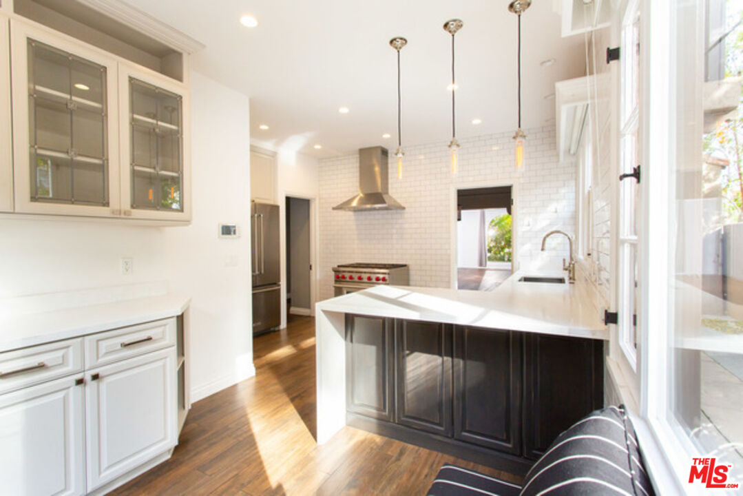 153 North Arnaz Drive Beverly Hills, CA 90211 - Photo 10 of 20 a kitchen with stainless steel appliances kitchen island granite countertop a sink a stove and a wooden floors