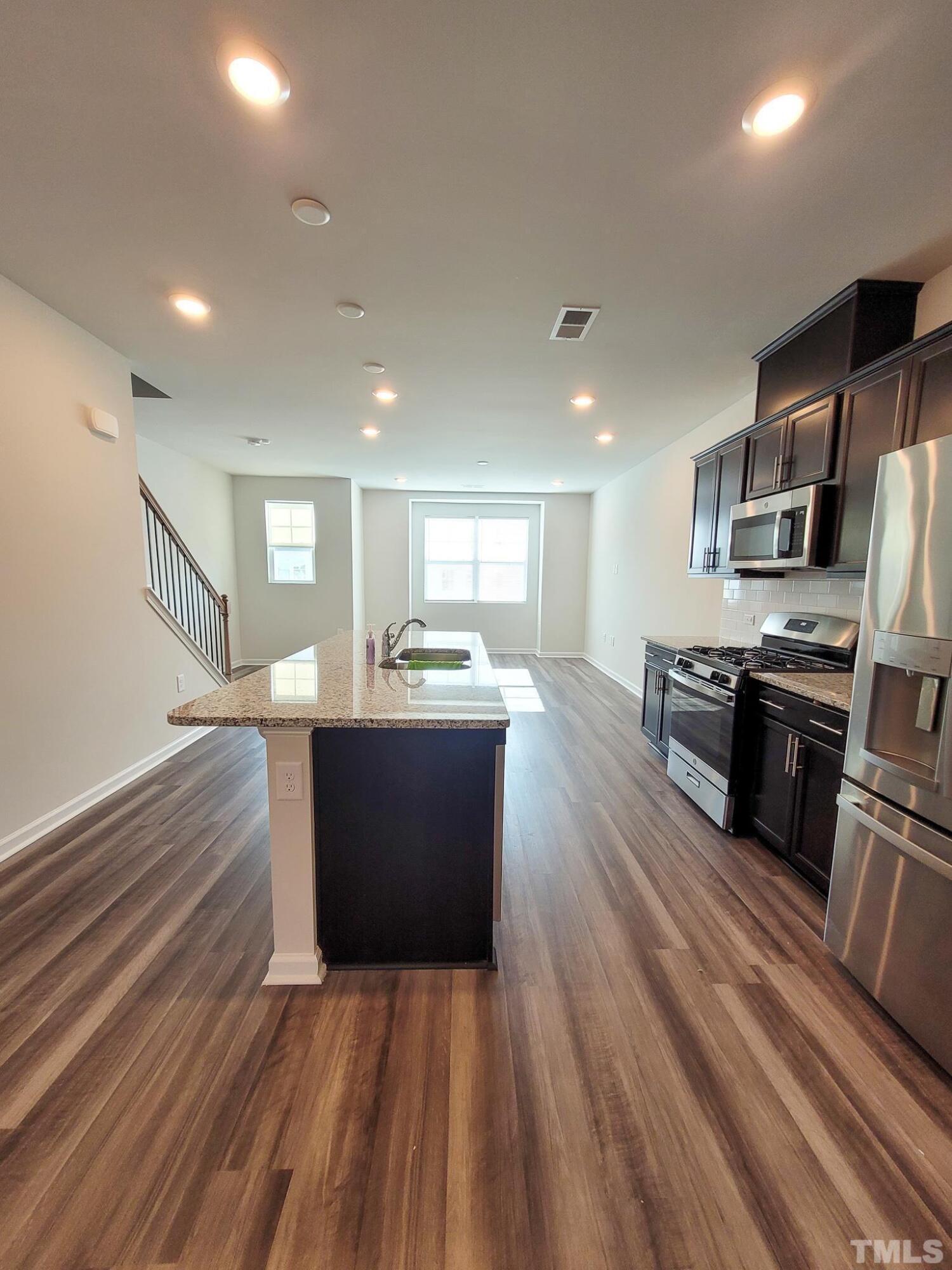 1038 Shoreside Drive Durham, NC 27713 - Photo 12 of 42 a large kitchen with stainless steel appliances a large counter top a stove and a refrigerator