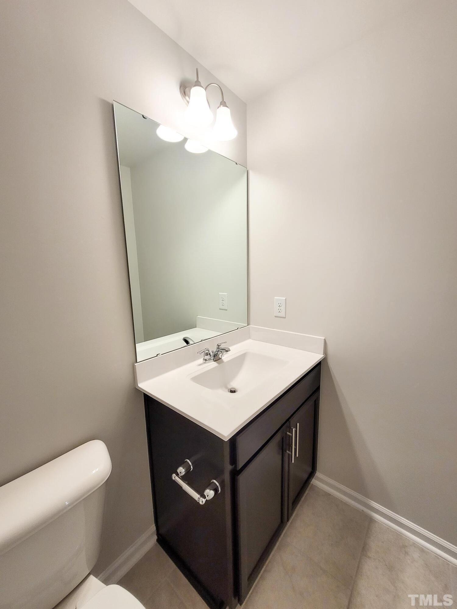 1038 Shoreside Drive Durham, NC 27713 - Photo 28 of 42 a bathroom with a sink a mirror and a toilet