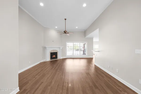 an empty room with wooden floor fireplace and windows