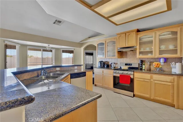 a kitchen with stainless steel appliances granite countertop a sink dishwasher stove and cabinets with wooden floor