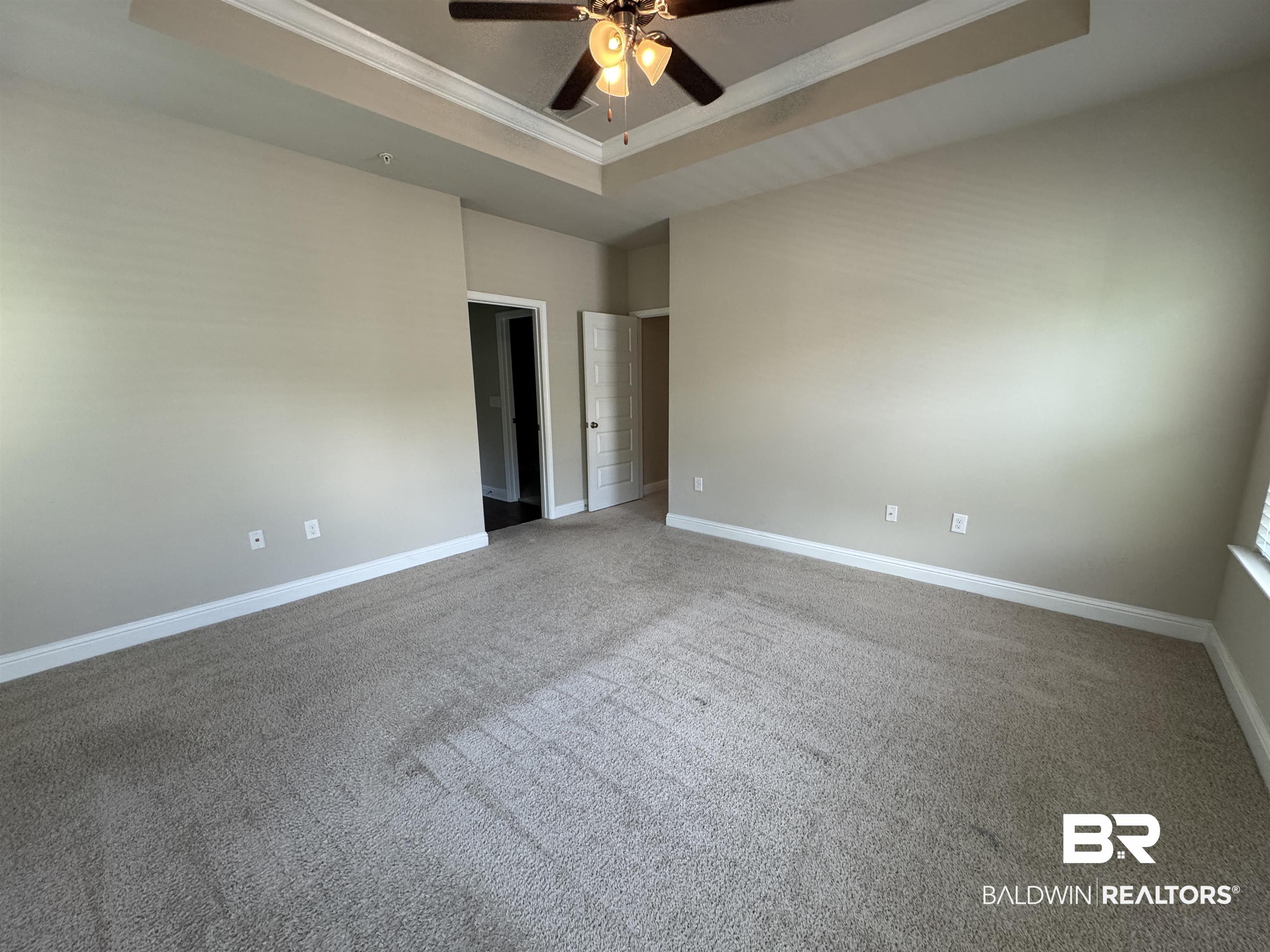 6811 Spaniel Drive, Unit C Daphne, AL 36527 - Photo 14 of 33 Carpeted spare room with a tray ceiling, ceiling fan, ornamental molding, and baseboards