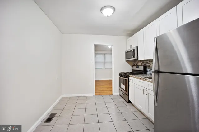 a kitchen with a refrigerator a stove top oven and cabinets